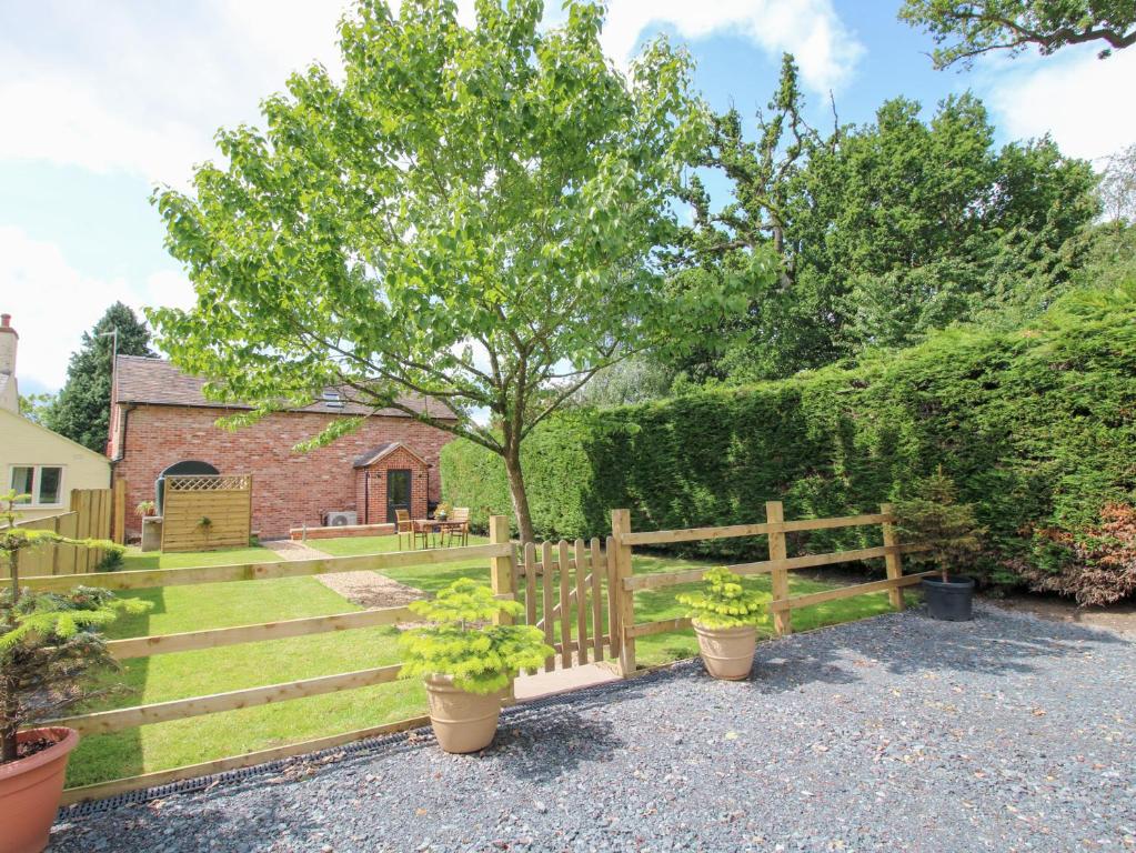 a garden with a wooden fence and a tree at Sylva Cottage in Shrewsbury
