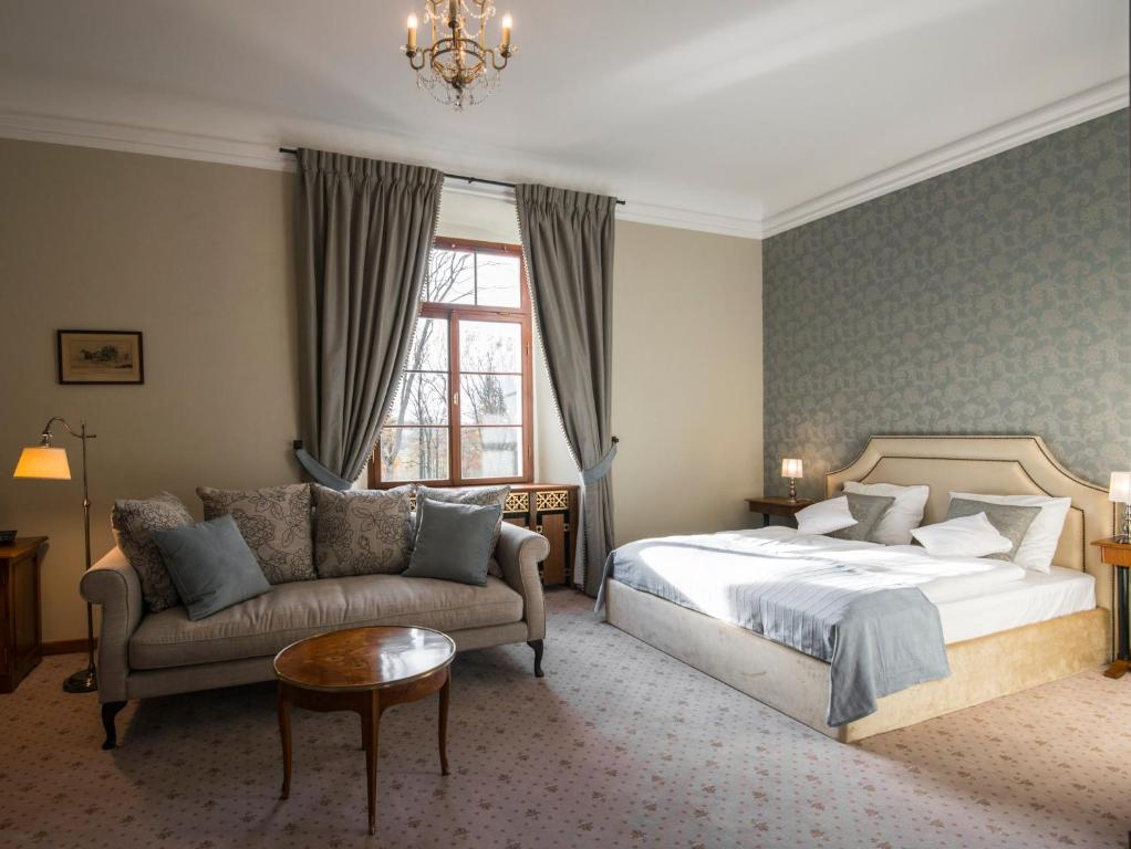 Sunlit bedroom with sofa, round coffee table, king bed, patterned accent wall and calm decor