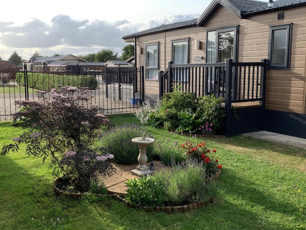 a garden in front of a house with a bird bath at Longdon Lodge in Evesham