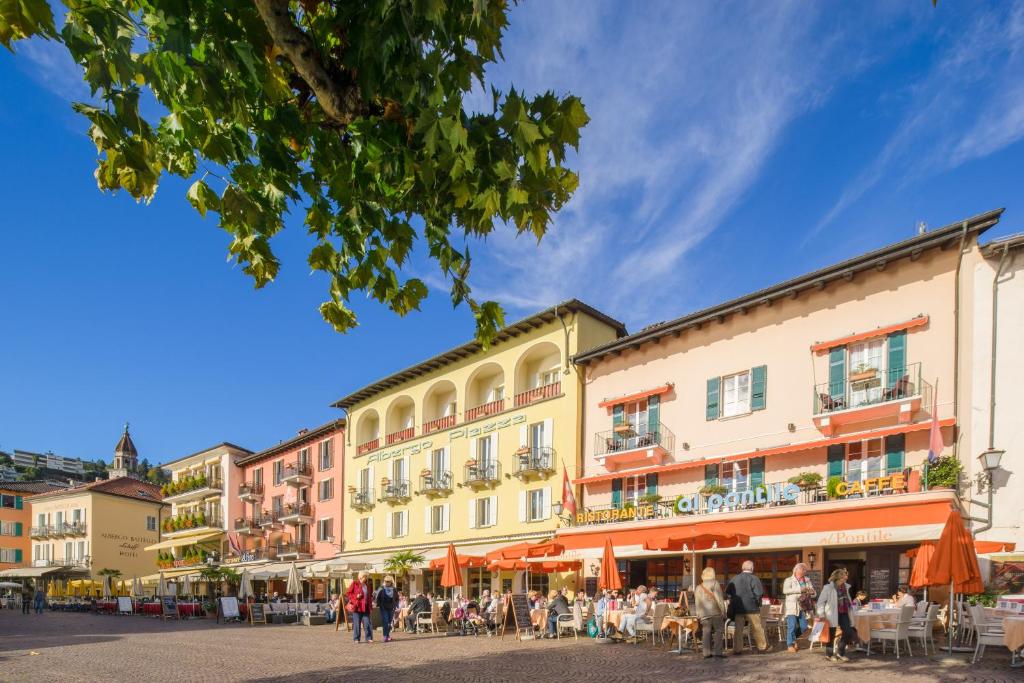 um grupo de pessoas andando em uma rua com edifícios em Piazza Ascona Hotel & Restaurants em Ascona