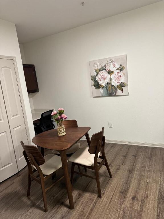 a dining room table with two chairs and a vase of flowers at Frisco Getaway in Frisco