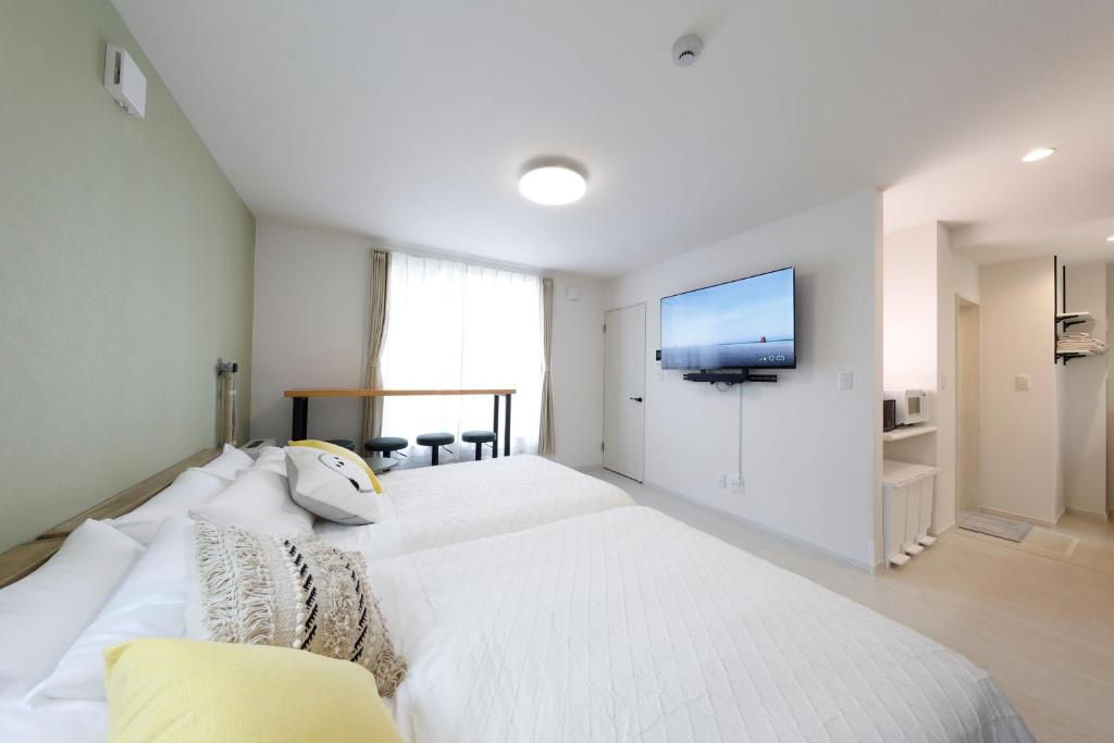 a bedroom with a white bed with a flat screen tv at わっず福住 in Tsukisappu