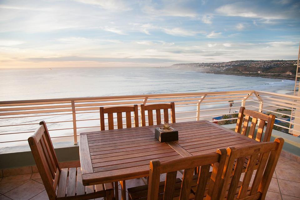 einen Holztisch und Stühle auf einem Balkon mit Meerblick in der Unterkunft Diaz Beach Apartment in Diasstrand