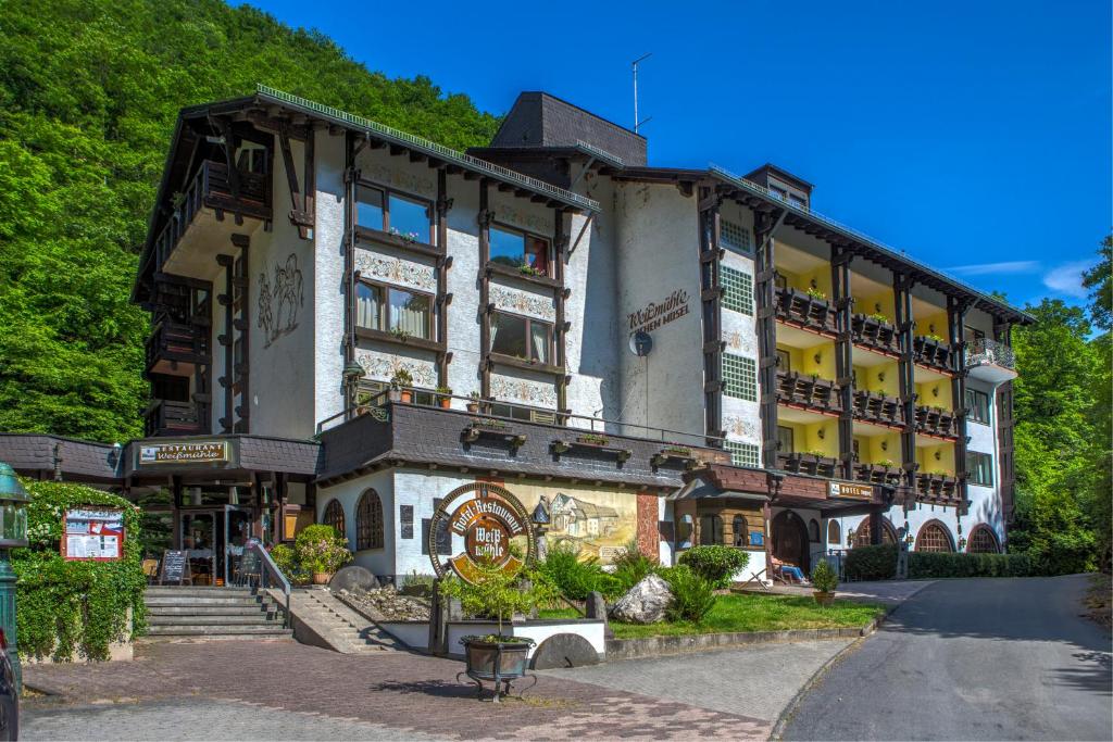 een groot gebouw in een straat naast een heuvel bij Moselromantik Hotel Weissmühle in Cochem