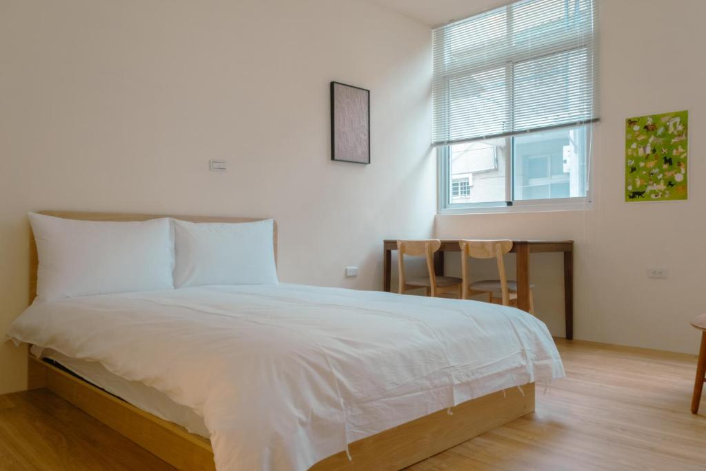 a bedroom with a bed and a table and a window at Bou house in Tainan
