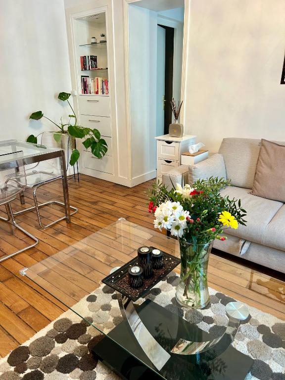 - un salon avec un vase de fleurs sur une table en verre dans l'établissement Résidence Renan - Paris Porte de Versailles, à Issy-les-Moulineaux