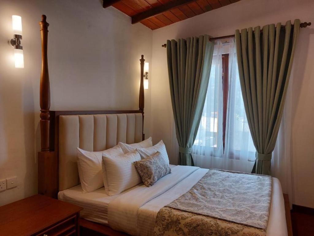 une chambre avec un grand lit avec une fenêtre dans l'établissement Hillwood Resort & Restaurant, à Hewaheta