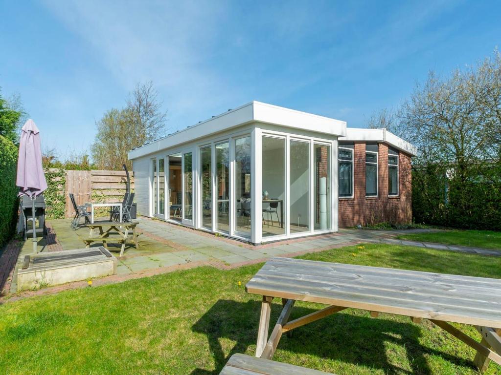 a screened in house with a picnic table in the yard at Bungalow with Sauna and Pool in Quiet Location in Sint Maartensvlotbrug