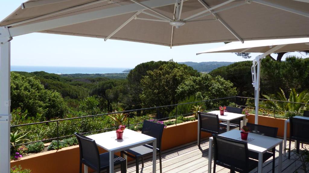 two tables and chairs on a deck with an umbrella at Hôtel les Bouis - Vue mer in Saint-Tropez