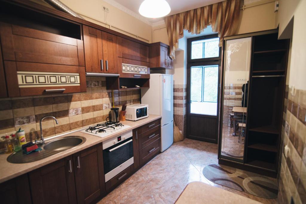 リヴィウにあるApartment on Bernarda Meretynaのキッチン(木製キャビネット、シンク、冷蔵庫付)