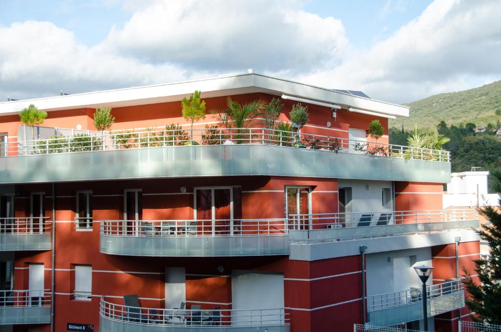 a red building with balconies and plants on it at Résidence Ambroise Paré in Lamalou-les-Bains