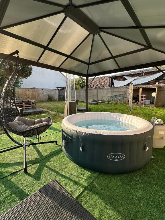 un grand parasol au-dessus d'un jacuzzi dans une cour dans l'établissement Maison 1 chambre Jacuzzi Privé, à Savigny-sur-Orge