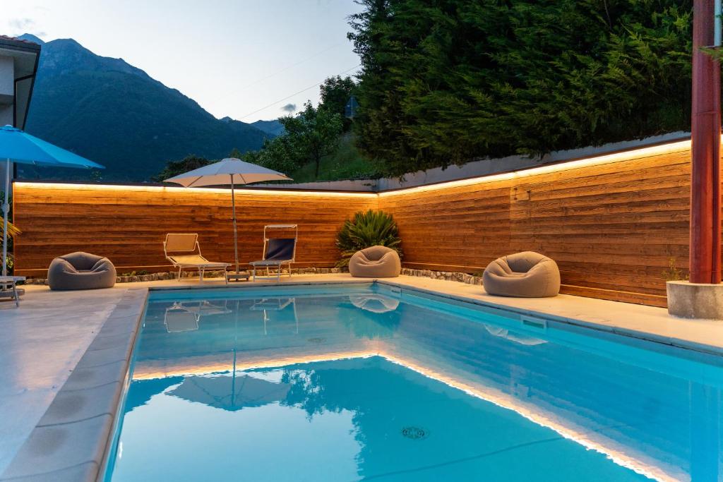 a swimming pool with a wooden fence and mountains at Infinity View Garda lake in Tenno