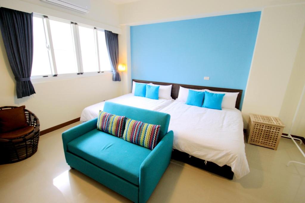 台東市的住宿－旅享家民宿，一间卧室配有一张大床和一张蓝色椅子