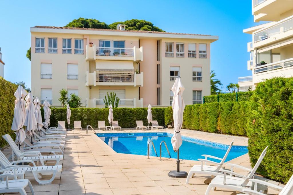 un hôtel avec des chaises et des parasols à côté d'une piscine dans l'établissement Bellevue Cannes, à Cannes
