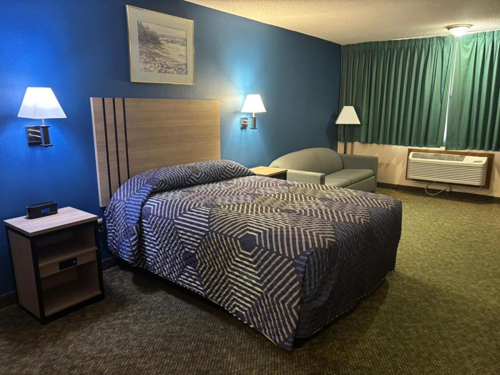 a hotel room with a bed and a chair at Capital O Marysville Surf Motel Kansas in Marysville