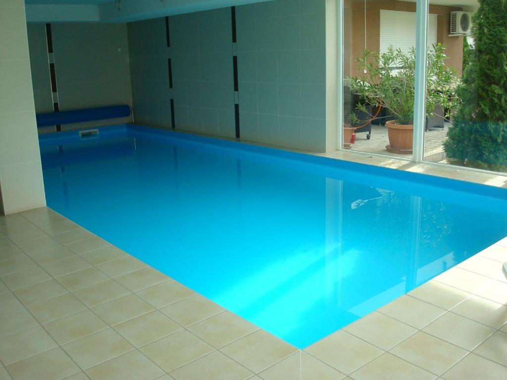 a large blue swimming pool in a house at Honey Wellness Apartman in Siófok