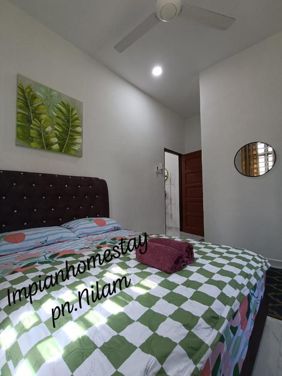 a bedroom with a bed with a checkeredkered bedspread at Impian homestay, wcy in Kota Bharu