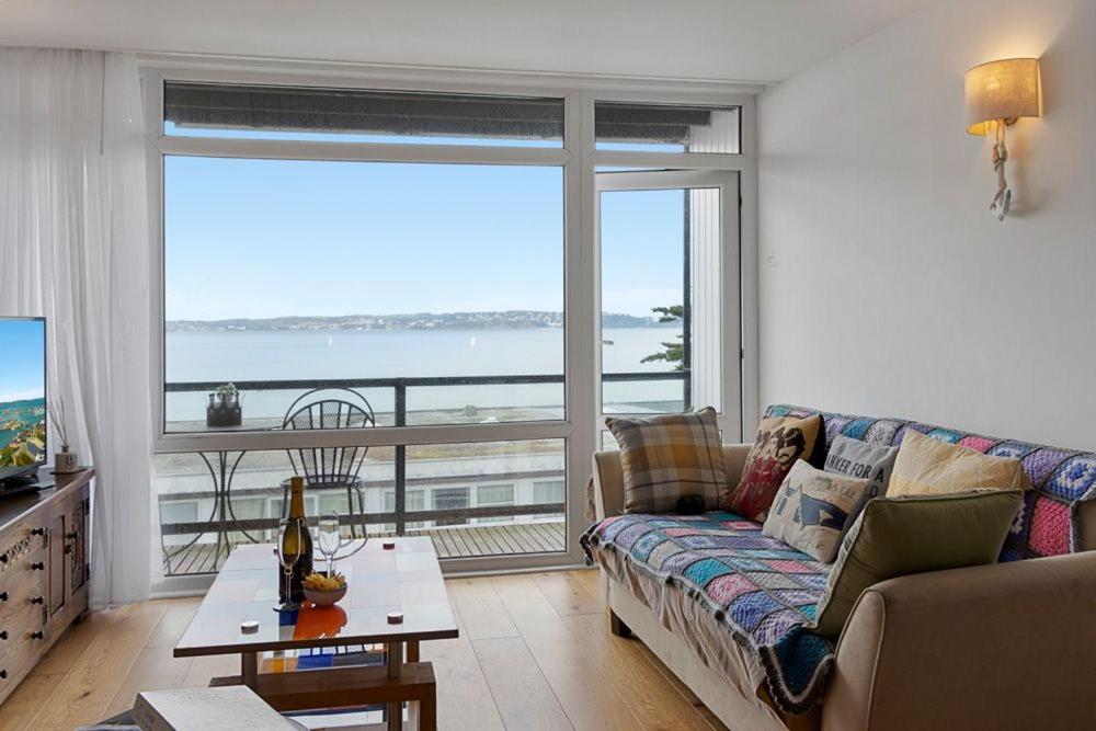Una sala de estar con un sofá y vista al mar. en Seaside Rendezvous - Sleeps 7, Sea Views & Parking, en Brixham
