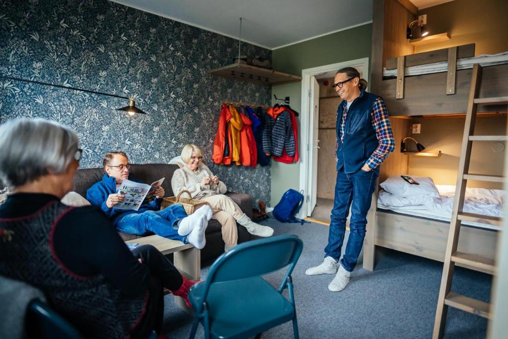 a group of people sitting in a room with bunk beds at Gårdshuset Vandrarhem in Undersåker