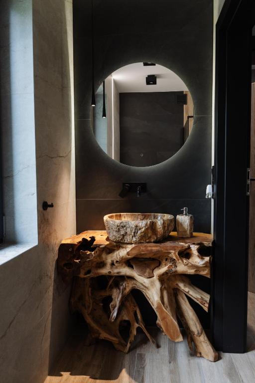 a bathroom with a large mirror and a wooden sink at W szczerym lesie - Domek z sauną i jacuzzi w lesie nad Jeziorem Mucharskim in Dąbrówka
