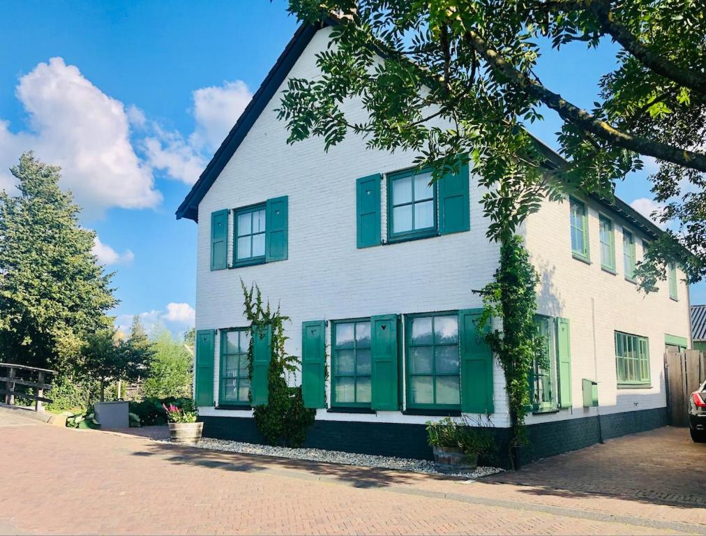 Casa blanca y verde con persianas verdes en Gieters Gruttertje Holiday Home, en Giethoorn