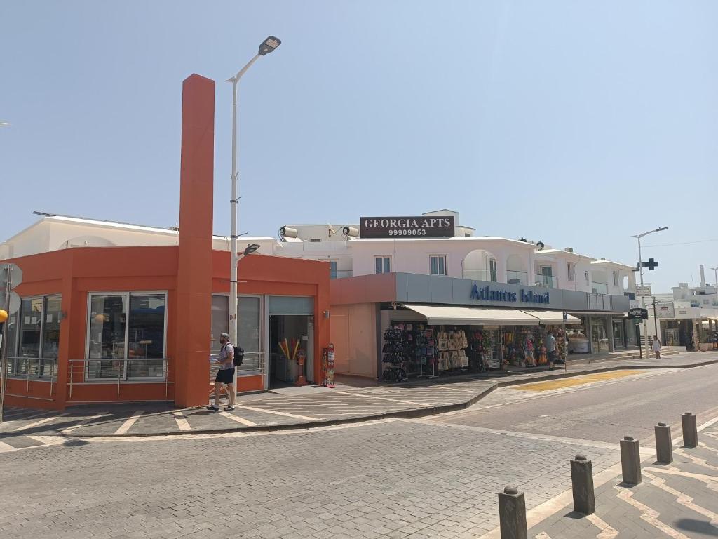 a person standing in front of a store on a street at Georgia Hotel Apartments in Protaras