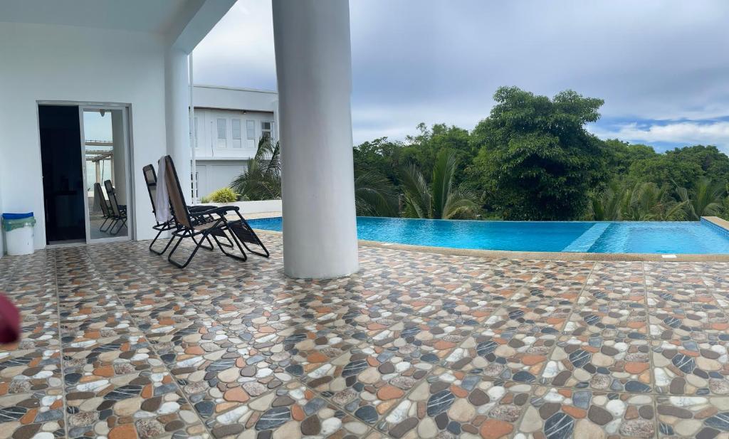 a patio with two chairs next to a swimming pool at Couple room C in Final Destination Resort in Bolinao