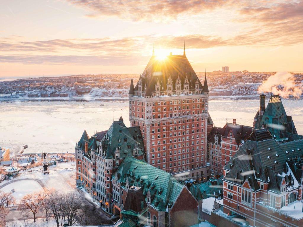 a large building with the sun shining on it at Fairmont Le Chateau Frontenac in Quebec City