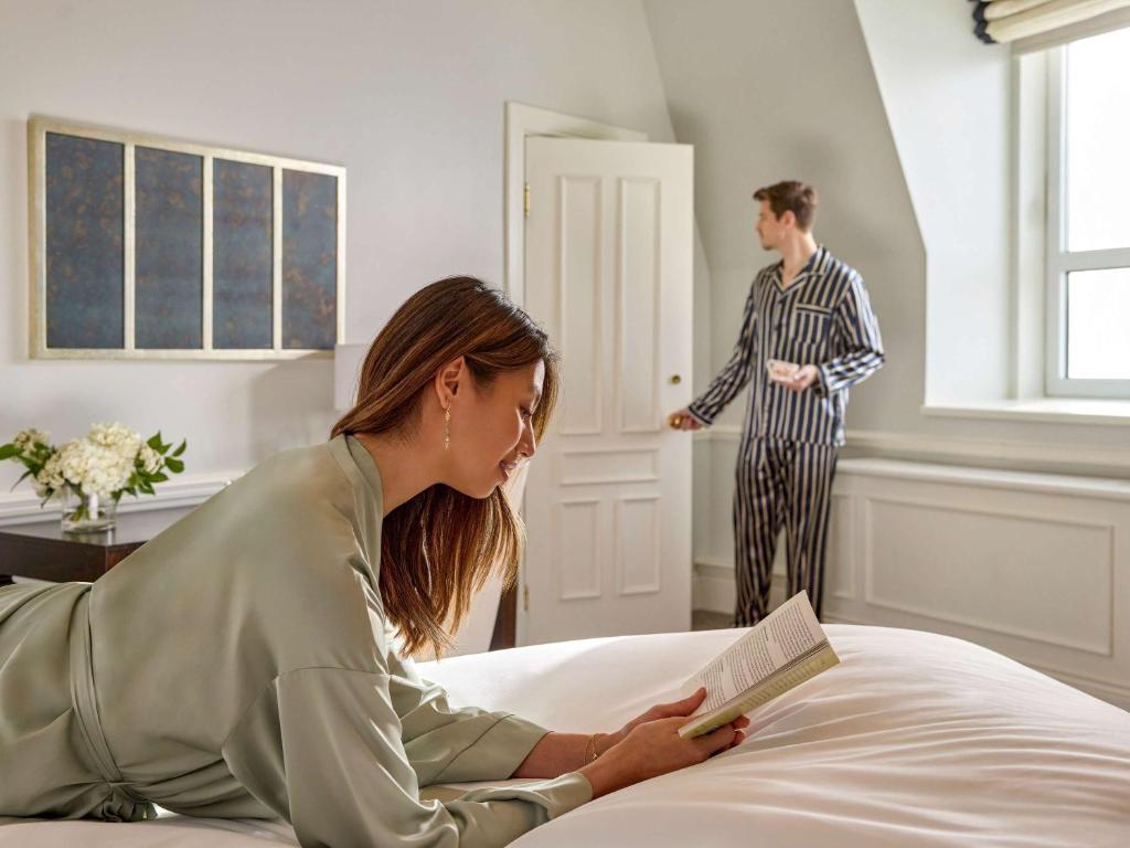 a woman laying on a bed reading a book with a man at Fairmont Le Chateau Frontenac in Quebec City