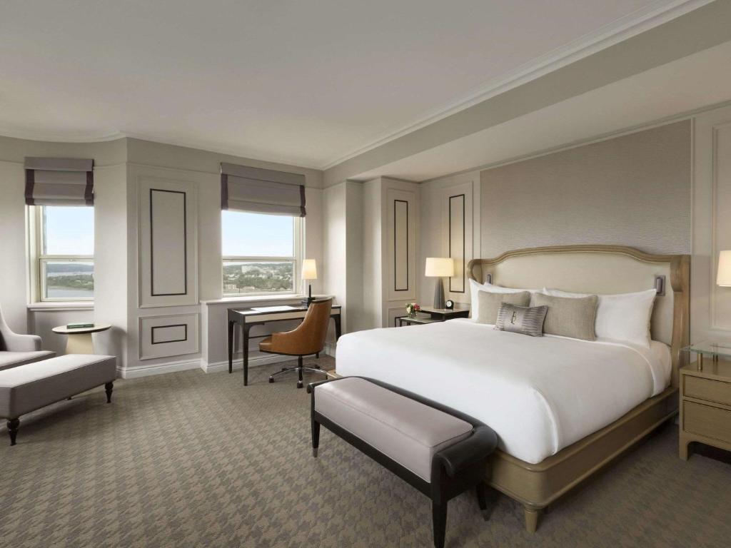 a bedroom with a large white bed and a desk at Fairmont Le Chateau Frontenac in Quebec City