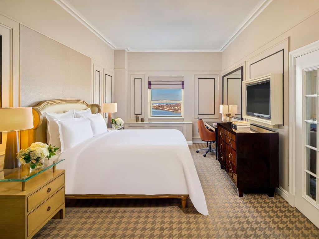 a bedroom with a large white bed and a television at Fairmont Le Chateau Frontenac in Quebec City