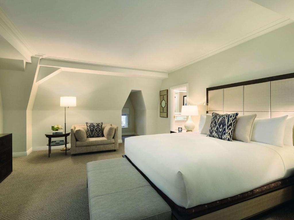 a bedroom with a large white bed and a chair at Fairmont Le Chateau Frontenac in Quebec City