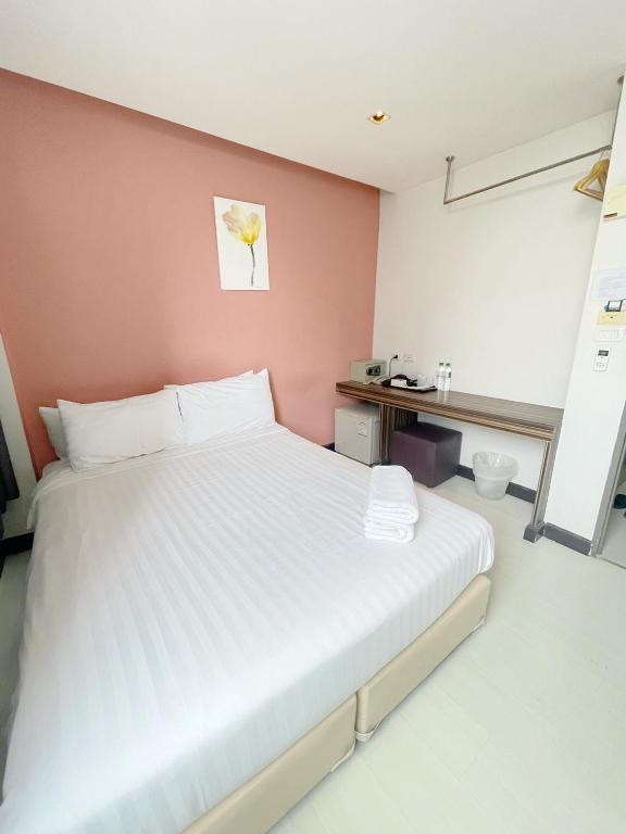 a bedroom with a white bed and a pink wall at Nantra Ekkamai Hotel in Bangkok