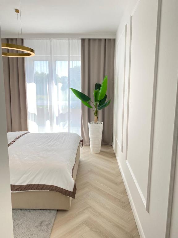a bedroom with a bed and a potted plant at Apartament DeLuxe Zamość Prywatny parking podziemny in Zamość