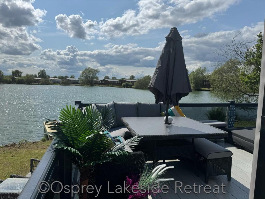 an umbrella sitting on a table next to a lake at Lakeside Retreat with hot tub and fishing peg on Osprey Rise at Tattershall Lakes Country Park in Tattershall