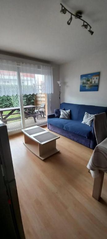 un salon avec un canapé bleu et une table basse dans l'établissement Appartement T2 cabine Berck rez de jardin parking, à Berck-sur-Mer