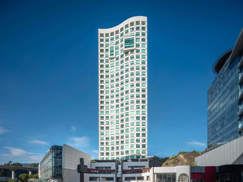 a tall white building with a blue sky at The Paragon Hotel Mexico Santa Fe By Accor in Mexico City