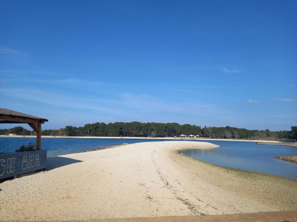 a sandy beach with a sign on it next to the water at Apartman Renata in Pula