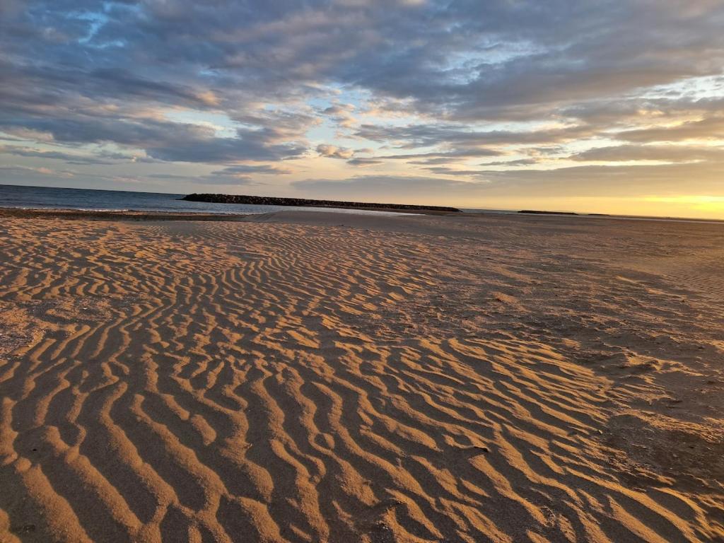 une plage avec des ondulations dans le sable au coucher du soleil dans l'établissement Maison moderne 300m de la plage rochelongue, au Cap d'Agde