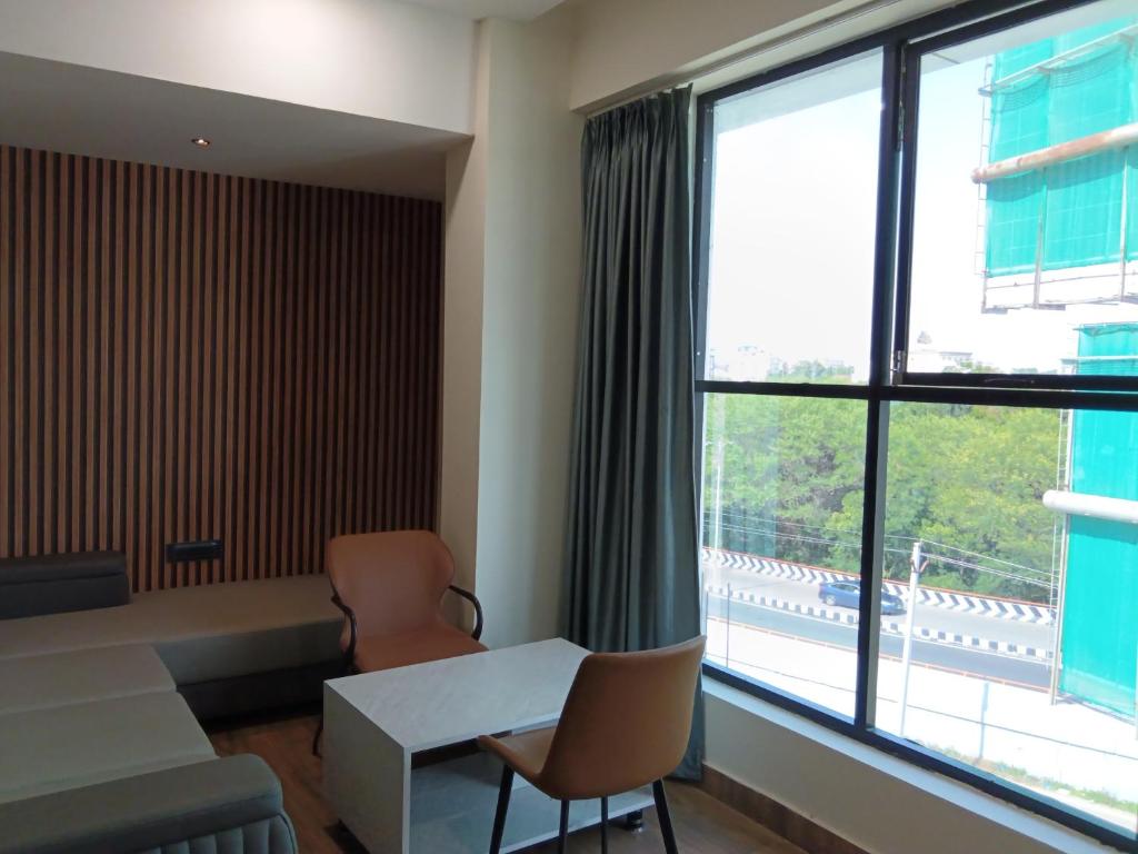 a living room with a desk and chairs and a large window at Hotel Vista Airport Zone in Shamshabad