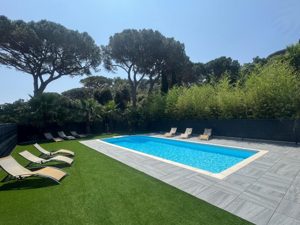 a swimming pool with lounge chairs on the grass at VILLA Azzurra in Sainte-Maxime