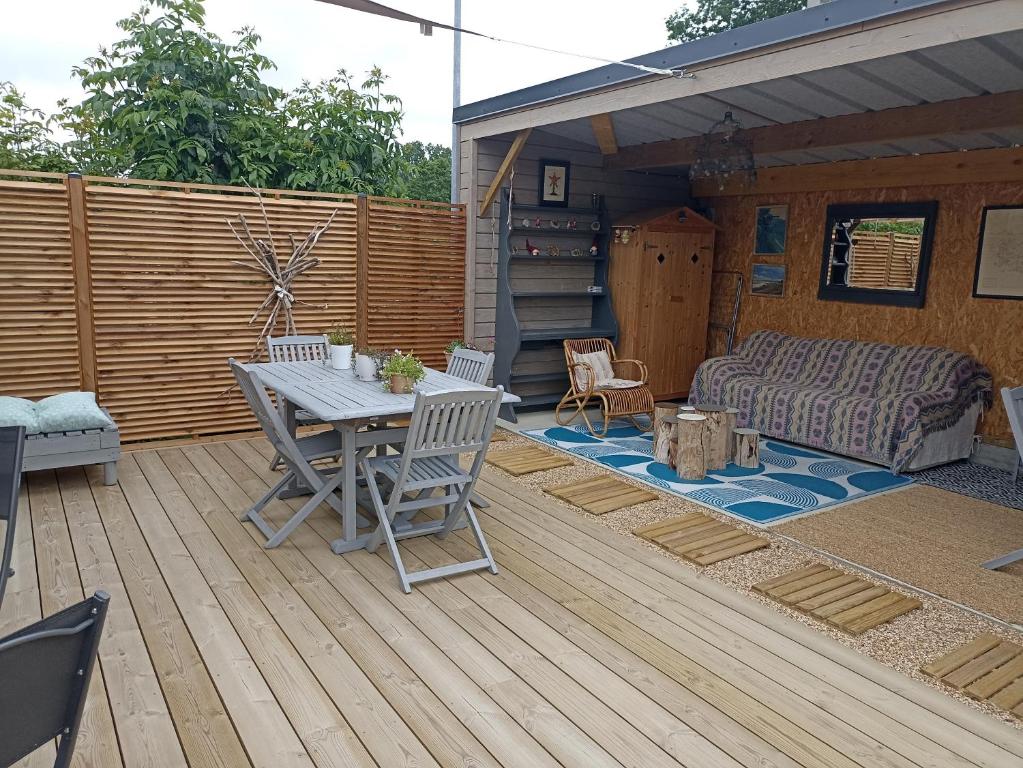 un patio avec une table et des chaises sur une terrasse dans l'établissement Le petit Préau 10 min plages, à Coudeville-sur-Mer