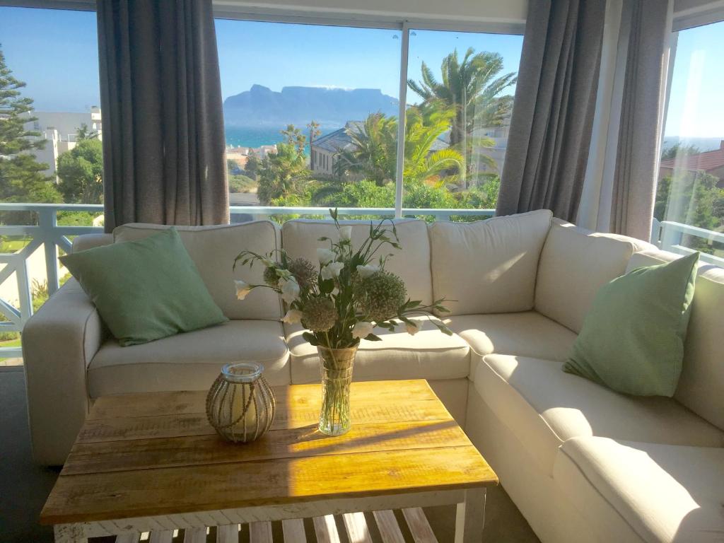 a living room with a white couch and a table at 5 Options Guest House in Bloubergstrand