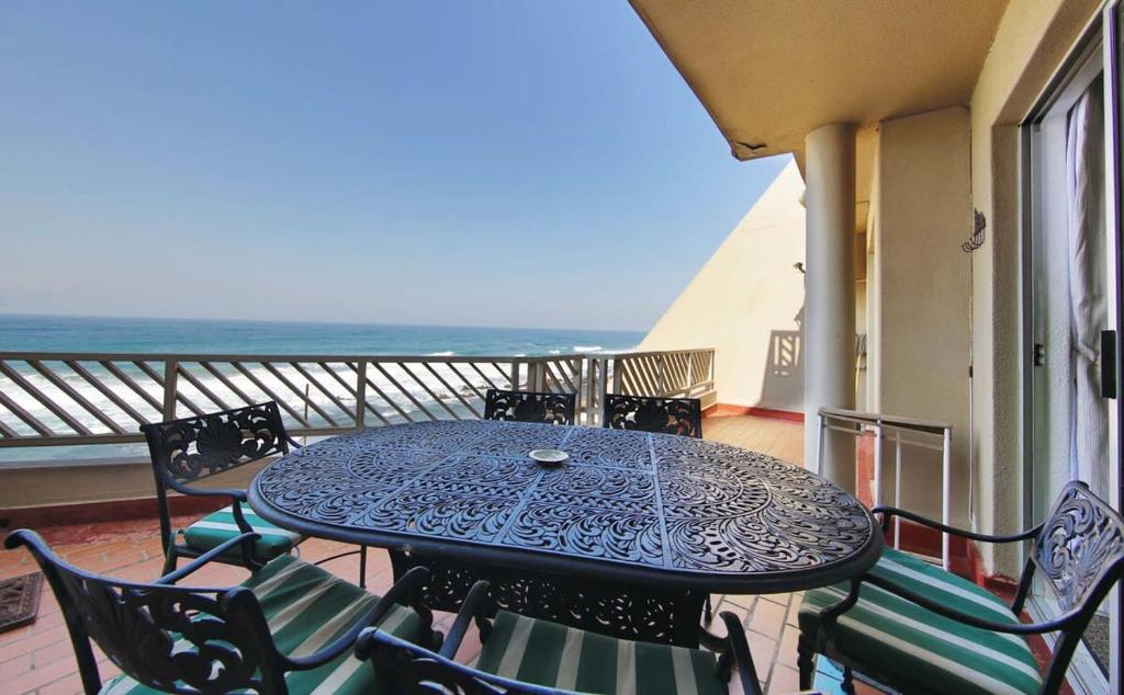 a table and chairs on a balcony with the ocean at 24 Isikhulu Umdloti Beachfront in Umdloti