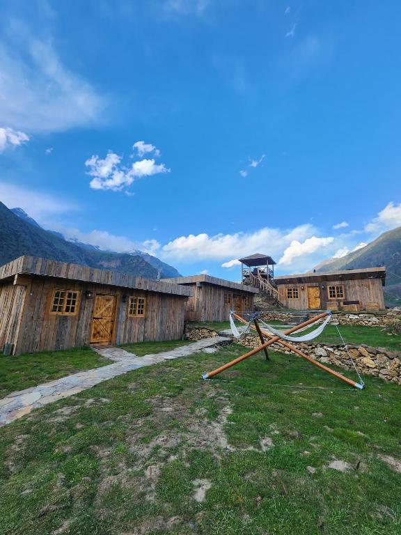 a couple of wooden buildings in a field at The Adventurers Resort in Dhechiān di Bahlk