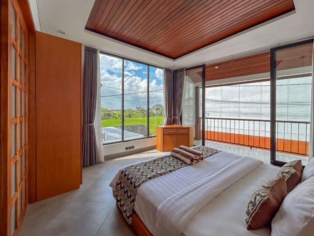 a bedroom with a large bed and large windows at Sudut Padi Villa Ubud by Omkara Experience in Ubud