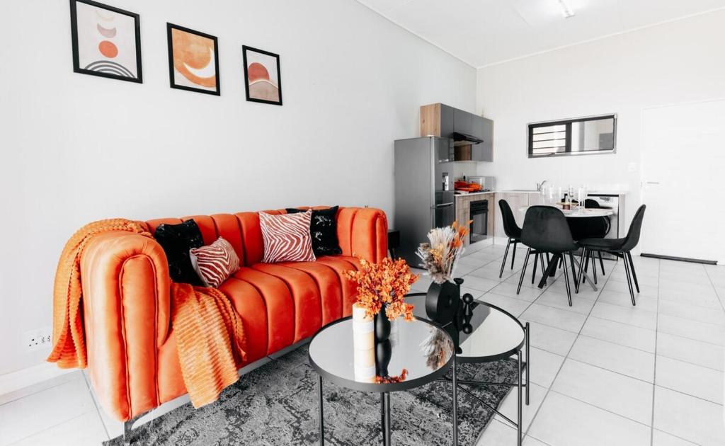 ein Wohnzimmer mit einem orangenen Sofa und einem Tisch in der Unterkunft Orange Blossom Luxury Apartment in Sandton