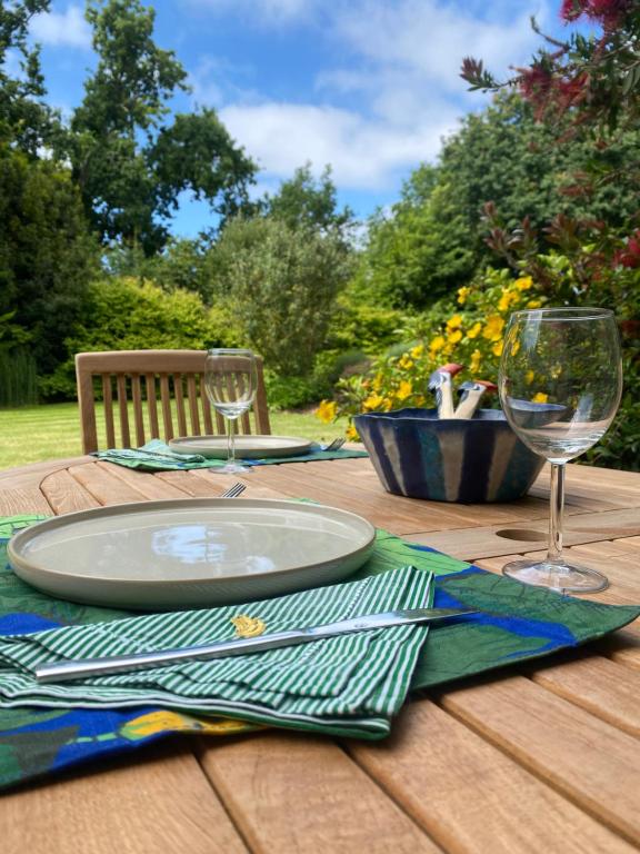 - une table en bois avec une assiette et des verres à vin dans l'établissement Les jardins de Beg Meil, à Beg-Meil