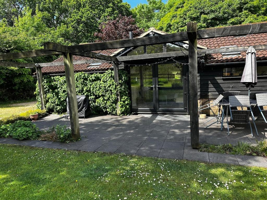 a wooden pergola with a table and chairs on a patio at Nature lovers retreat - New Forest in Ibsley